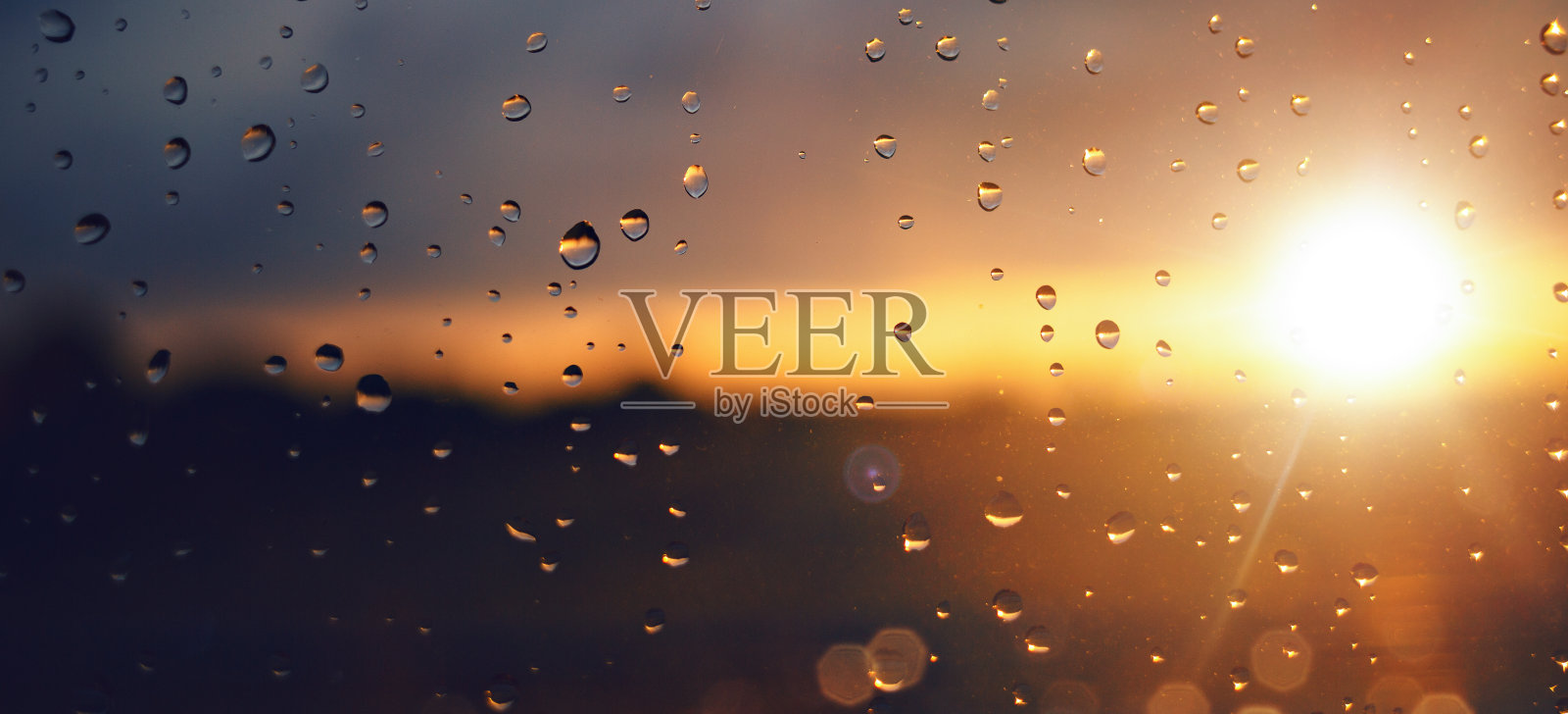 夕阳下的雨滴落在窗玻璃上照片摄影图片