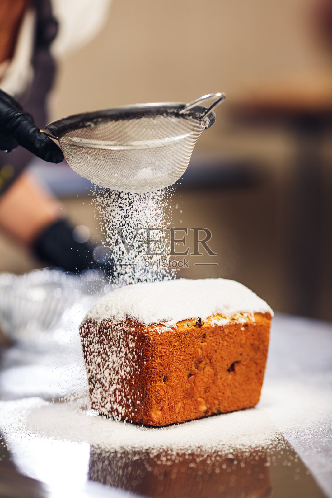 糖果师傅用筛子在复活节蛋糕上撒糖粉。照片摄影图片