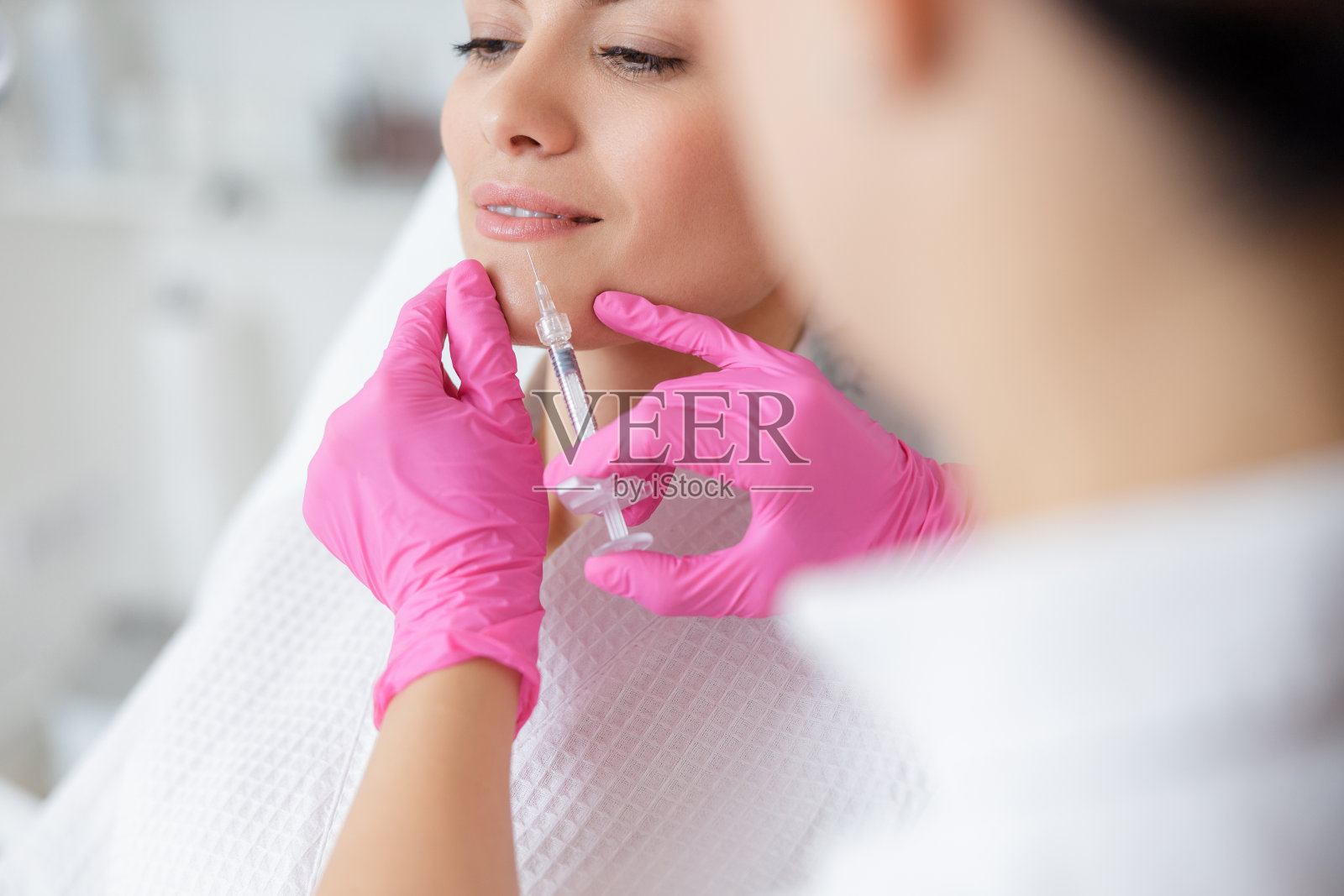 微笑的女士接受美容注射在水疗沙龙照片摄影图片