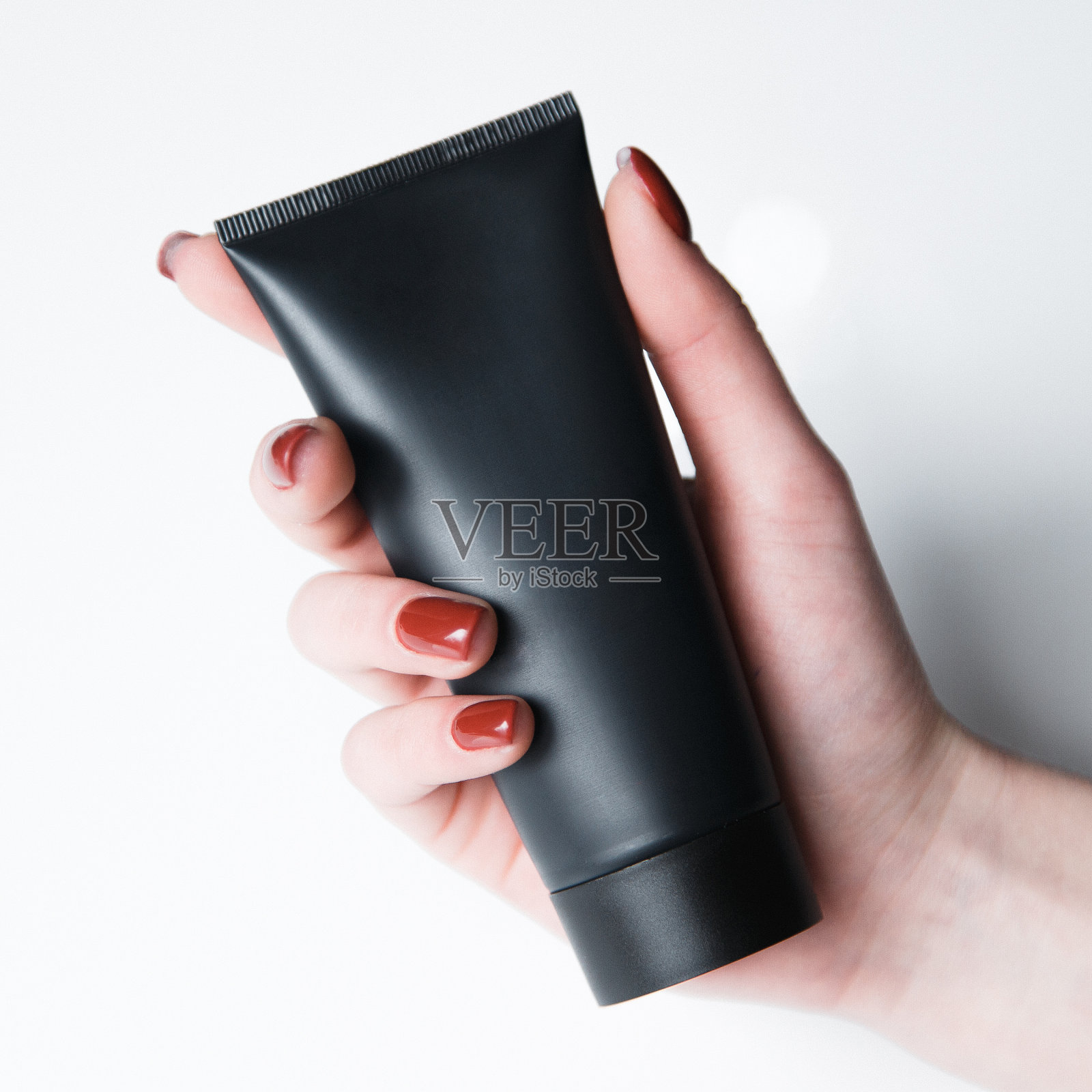 白色背景上的化妆罐和化妆管。手上拿着一套化妆品。照片摄影图片