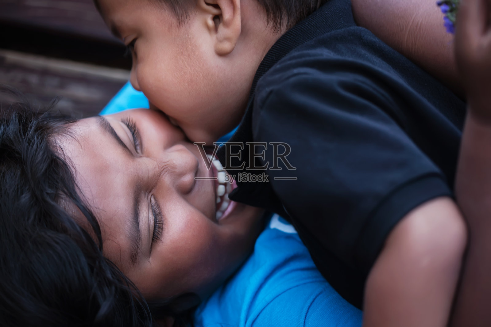 一个小弟弟给了他的姐姐一个吻在她的脸颊上，她大声笑了出来。照片摄影图片