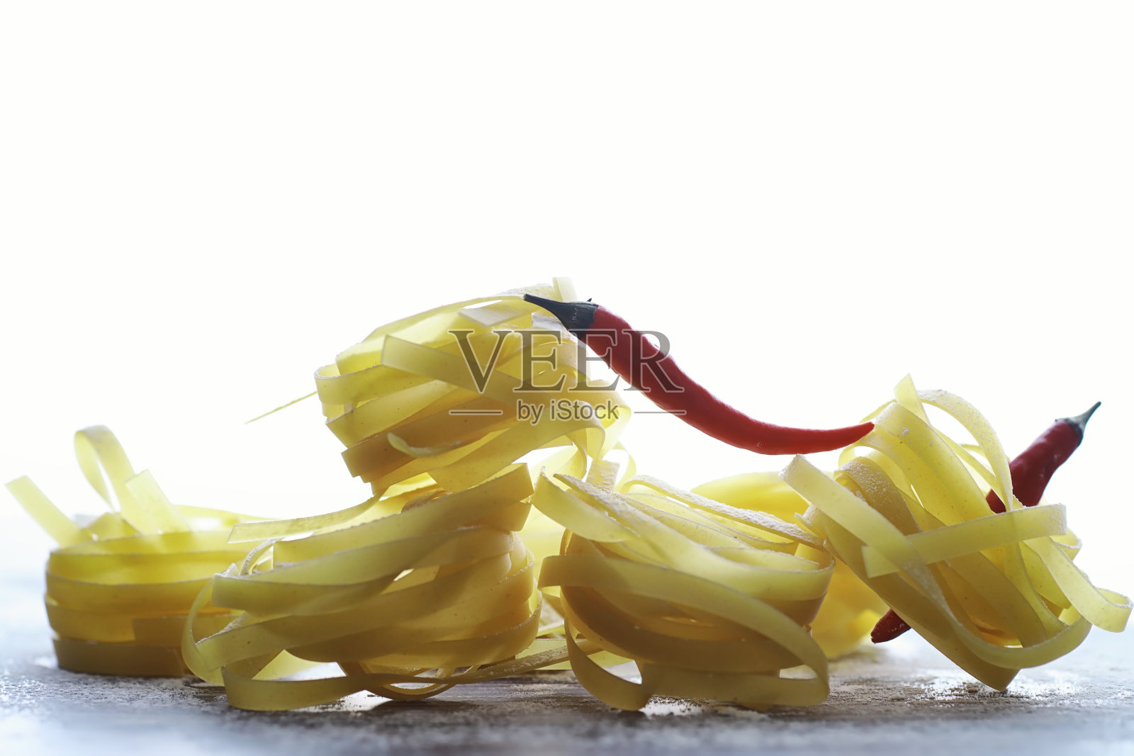 桌上有生的意大利面。巢形面条。照片摄影图片