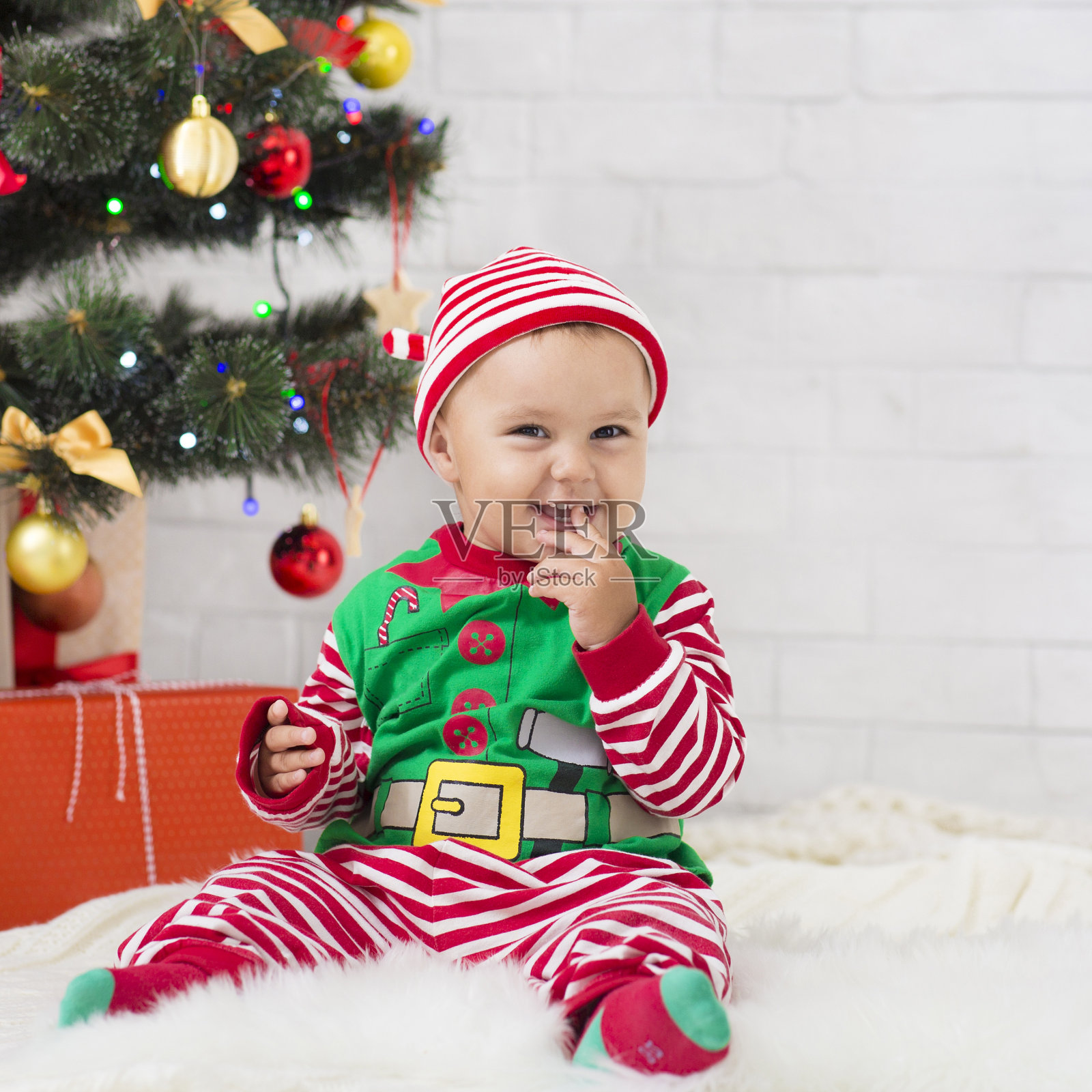 可爱的小精灵在圣诞树下享受甜蜜的棒棒糖照片摄影图片