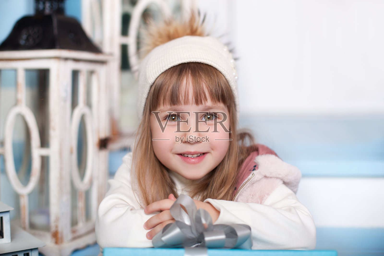 圣诞快乐，节日快乐!新年。一个戴着帽子的可爱小女孩坐在冬天的门廊上。孩子坐在阳台上的木楼梯上。圣诞夜。孩子打开新年礼物。照片摄影图片