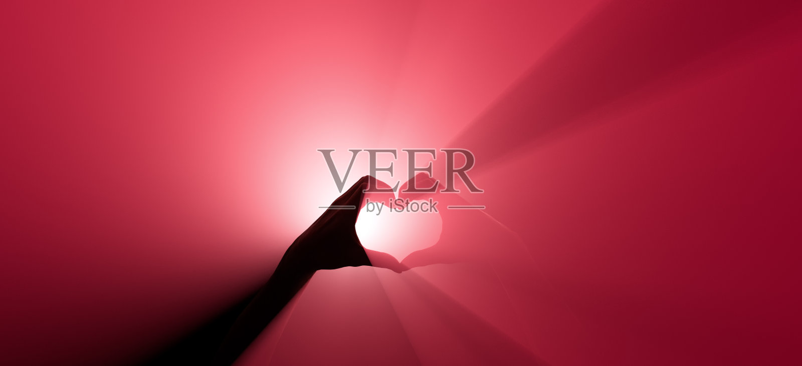 一个手势象征着爱。背景是红色聚光灯。照片摄影图片