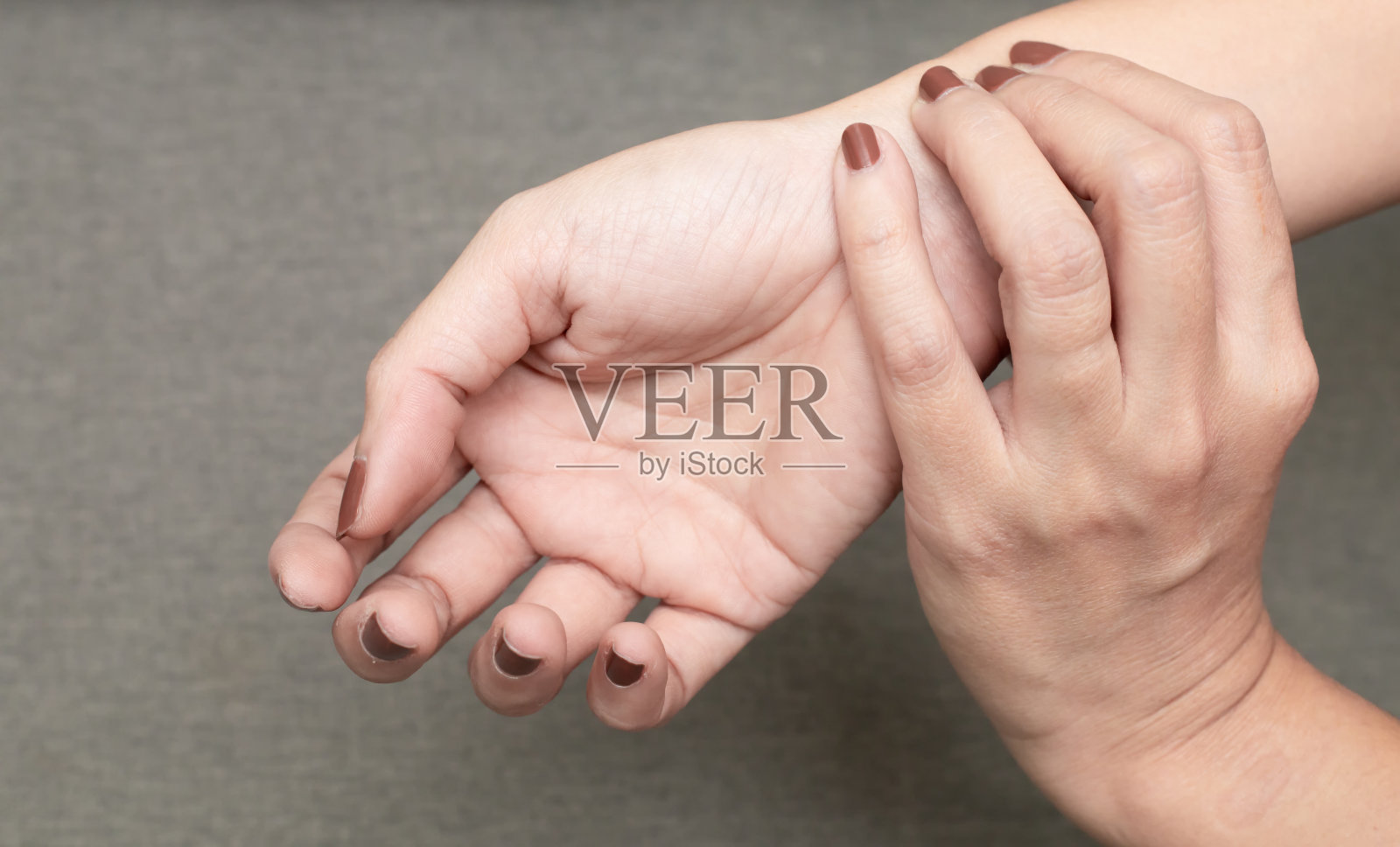 女人握着她的手腕。患有腕管综合症或检查脉搏照片摄影图片