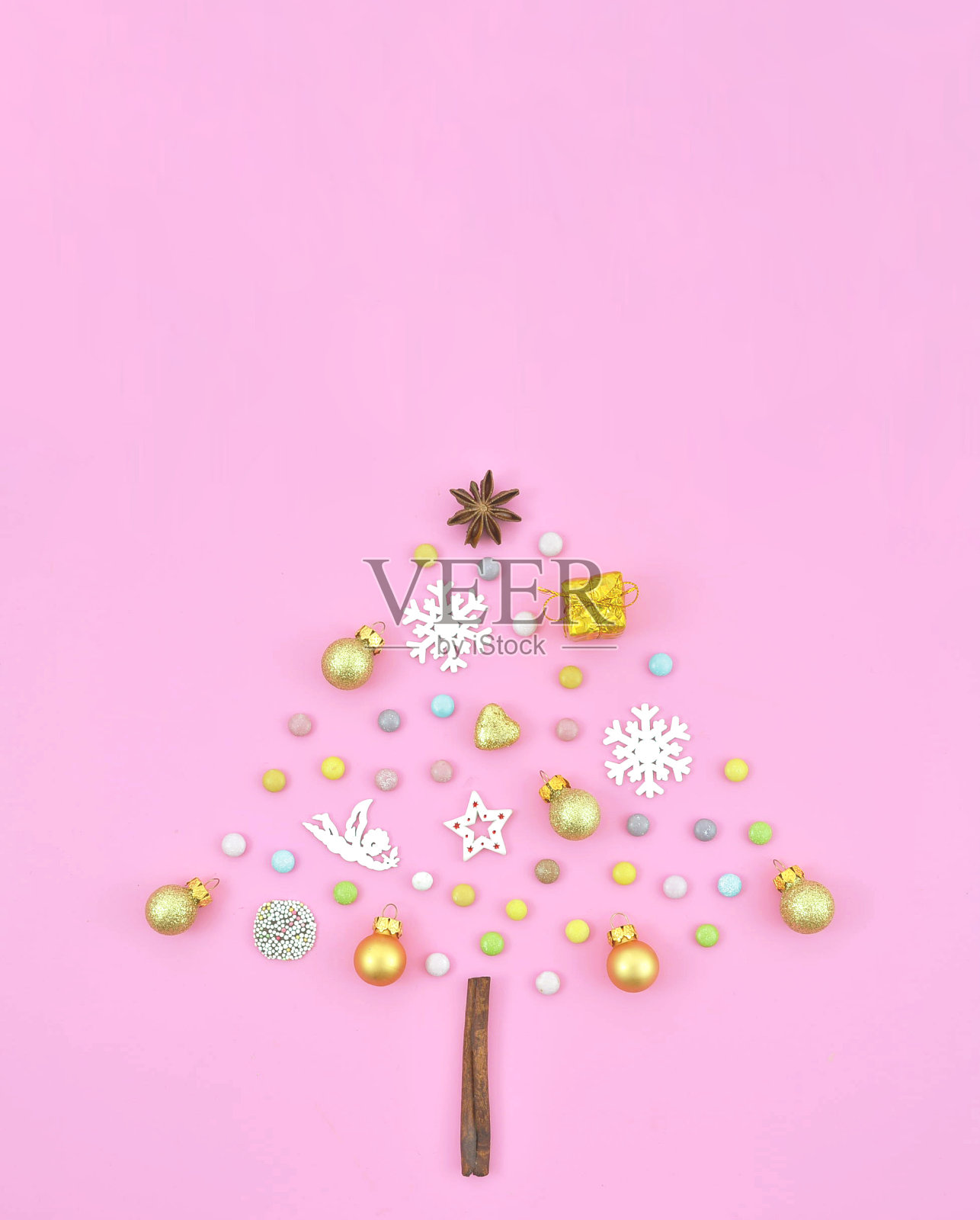 俯视图彩色圣诞树形状的新年装饰在粉红色的背景。礼品盒，球，圆锥，金色的亮片。平lay节日贺卡的概念照片摄影图片
