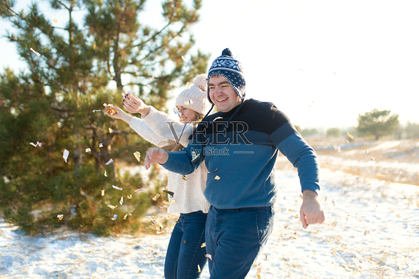 那家伙和那女孩在冬天的森林里扔五彩纸屑照片摄影图片