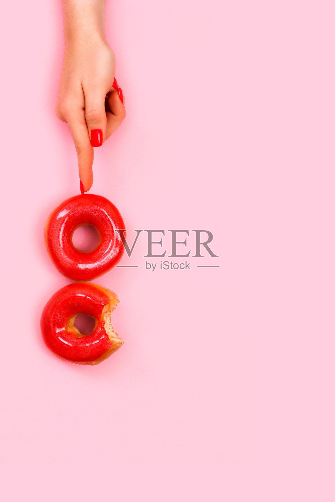 一个女人的手有一个美丽的时尚美甲拿着两个甜甜圈闪闪发光的手指。照片摄影图片