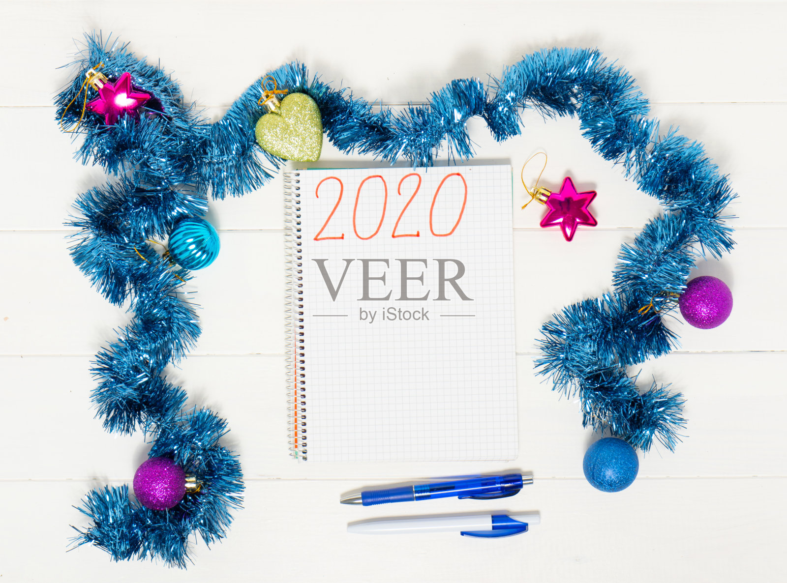 新年目标用彩色的装饰放在白色木制的桌子上。笔记本与钢笔和圣诞装饰。照片摄影图片
