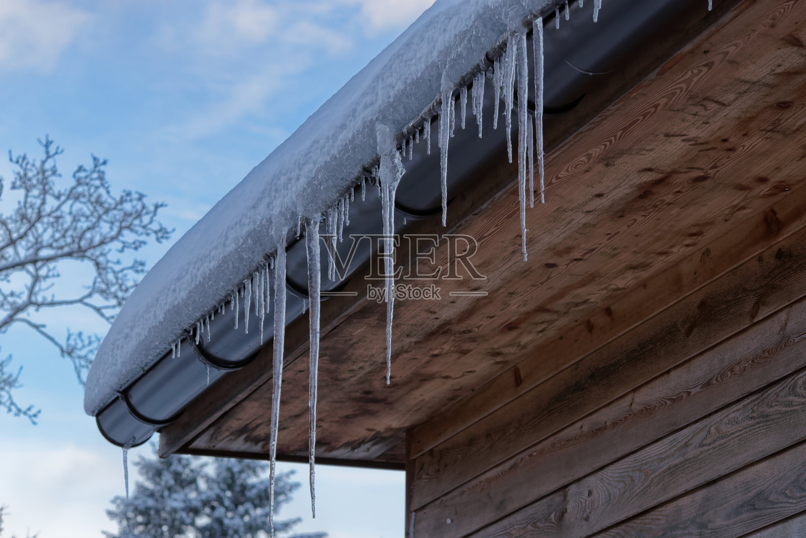 悬挂在木屋屋顶上的冰柱的特写照片摄影图片