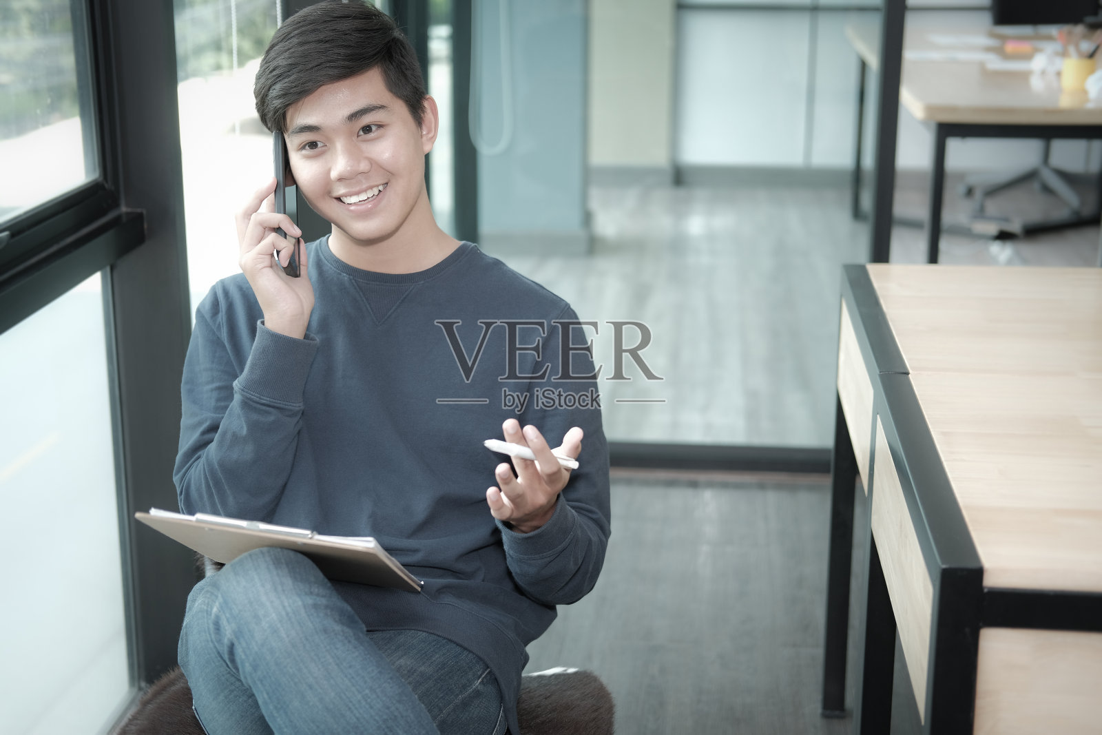 男性自由职业者在办公室用智能手机聊天。亚洲自由职业男性女性企业家与文件工作。经营理念照片摄影图片