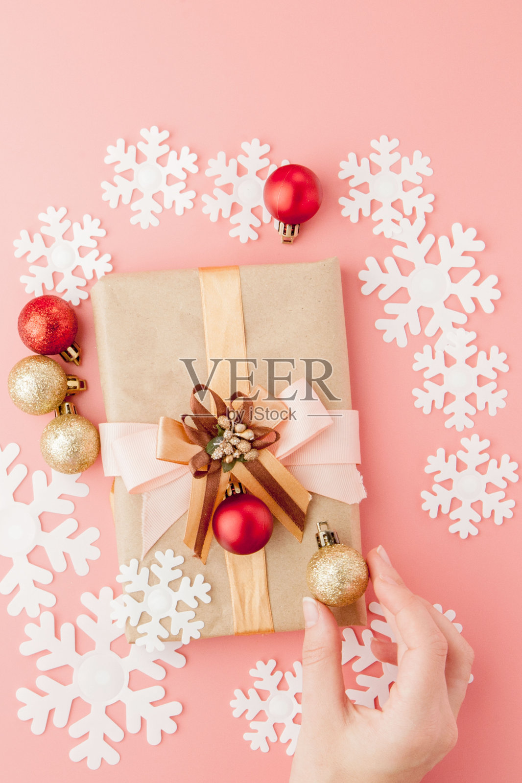 女士手握礼物，粉红色背景上有蝴蝶结。节日背景:生日，情人节，圣诞节，新年。平躺照片摄影图片