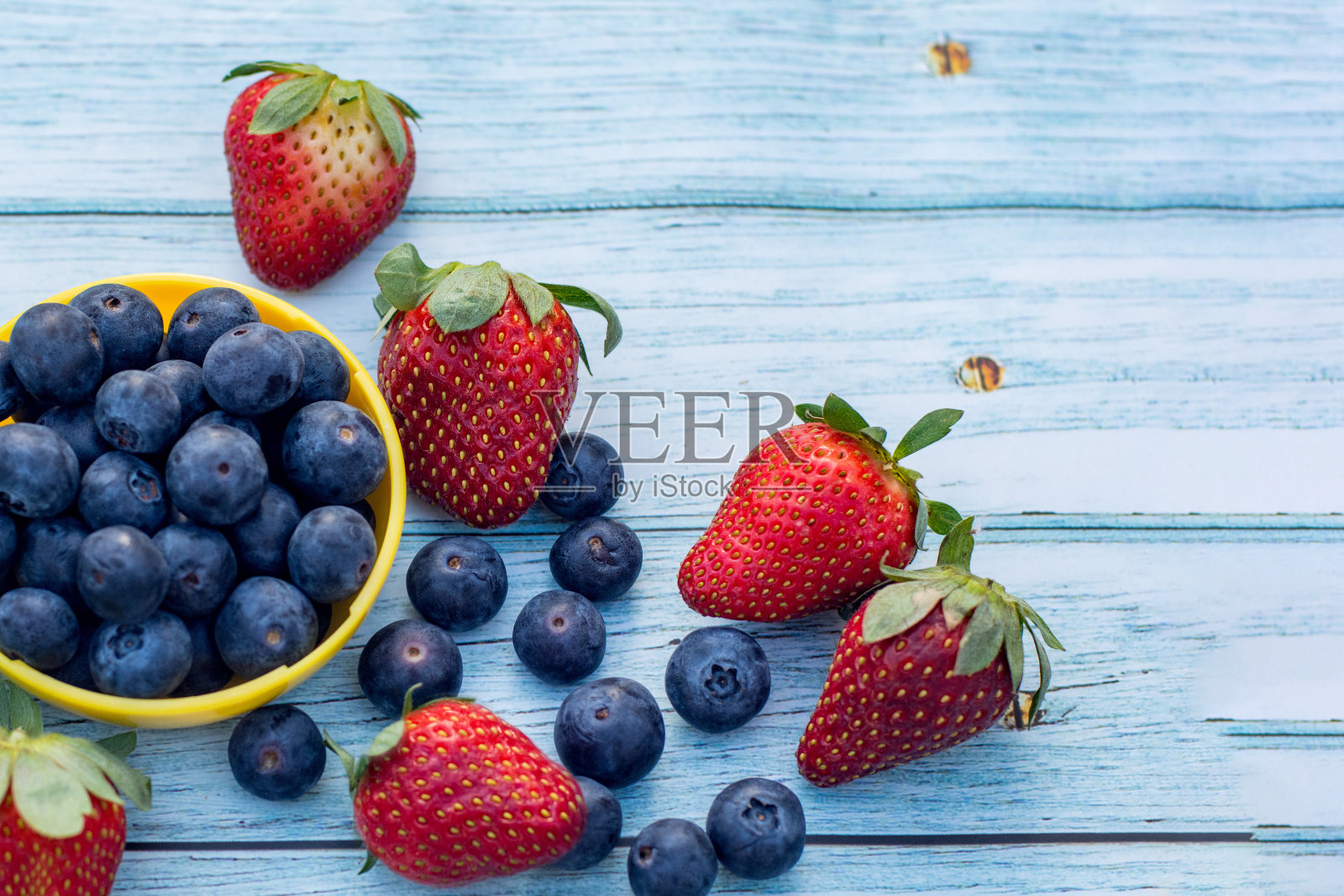碗里装着蓝莓，木背景上放着草莓。健康的生活方式的概念照片摄影图片
