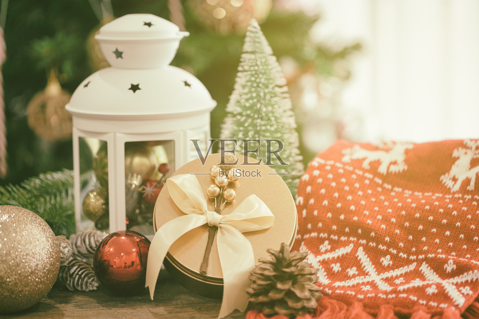 圣诞背景装饰用白灯笼、松叶、松果、球和豪华的金色礼盒放在有拷贝空间的木桌上。散景圣诞树墙纸庆祝圣诞。照片摄影图片