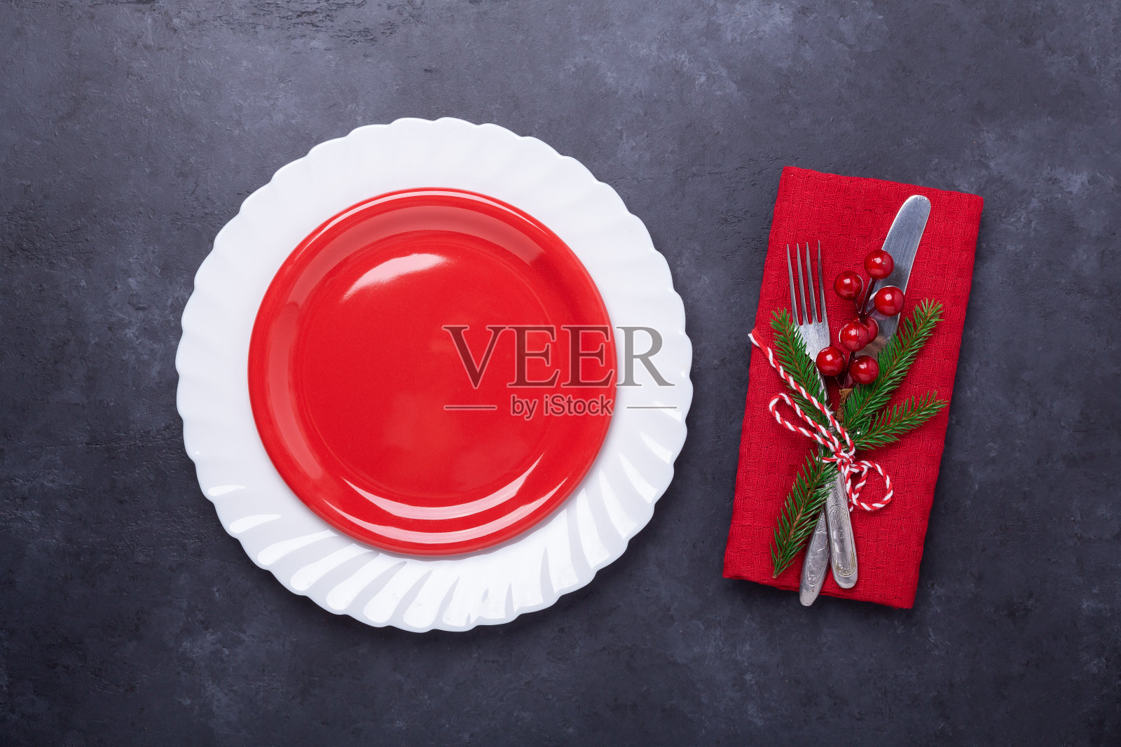 圣诞餐桌的地方设置与空红色盘子，餐具与节日装饰星弓球在石头的背景照片摄影图片