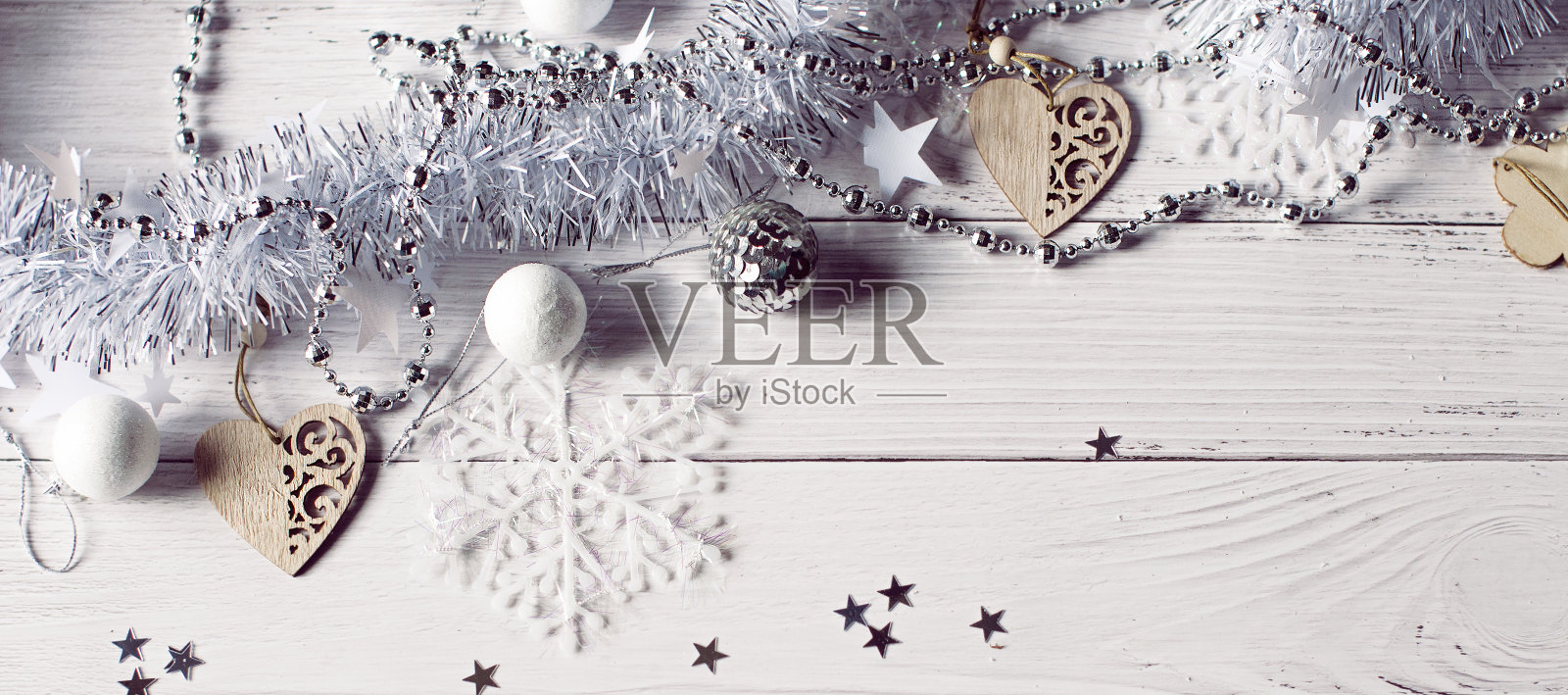 圣诞背景的银箔，珠子，木制圣诞玩具，雪花和星星躺在一个白色的木制桌子上照片摄影图片