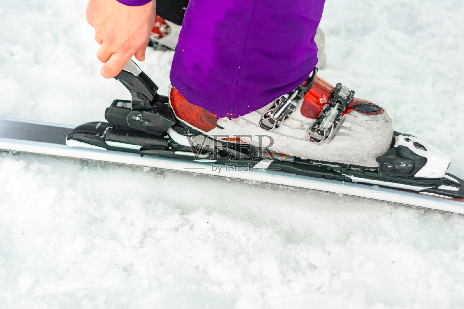 滑雪者在腿上演示一套滑雪板和靴子。照片摄影图片