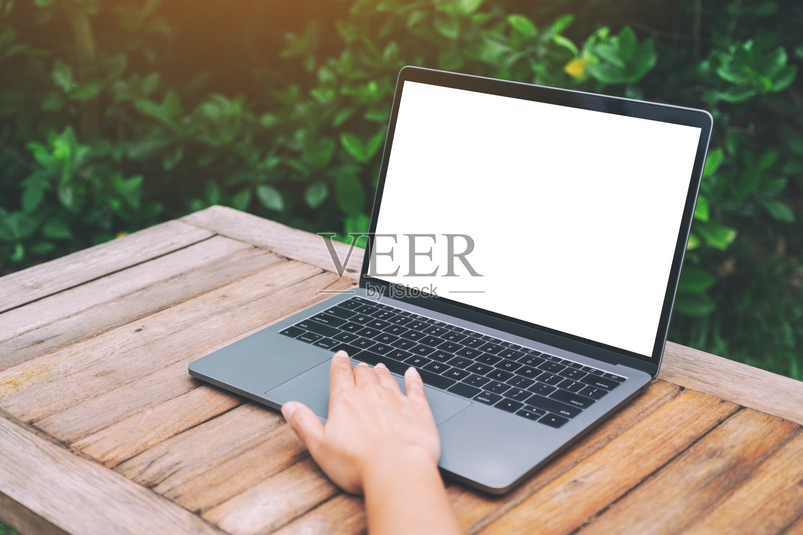 一个女人正在使用并触摸笔记本电脑的触控板，木桌上的白色桌面屏幕是空白的照片摄影图片