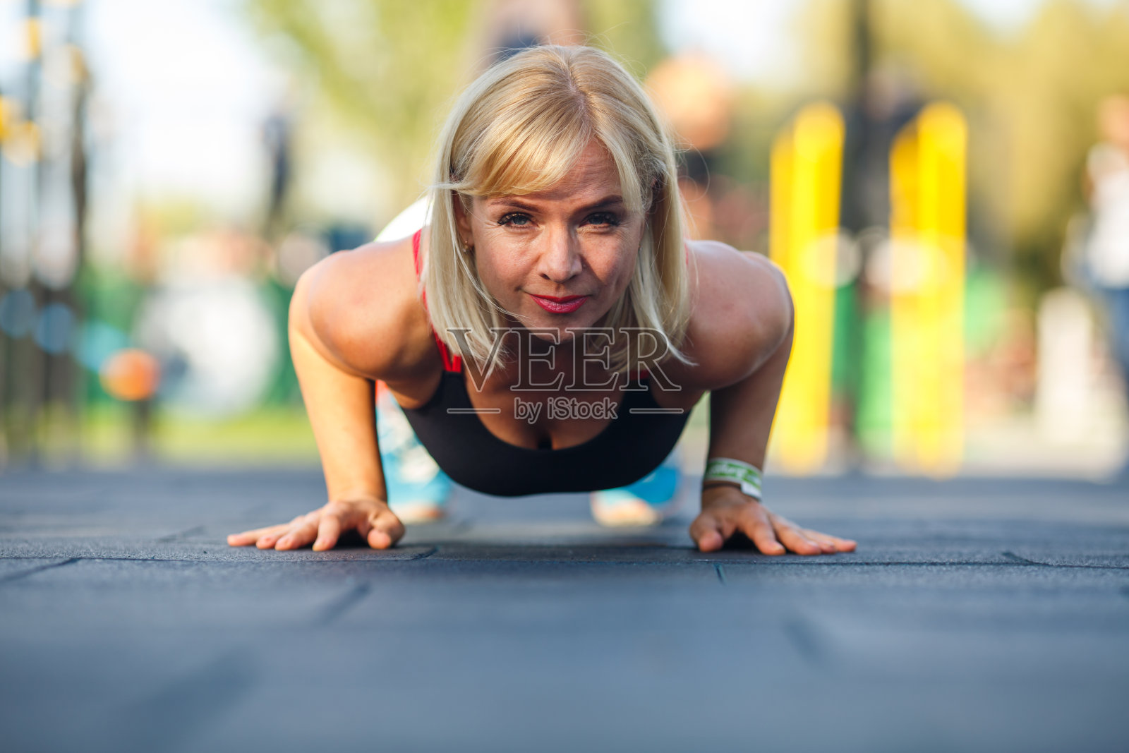 美丽成熟的女人在一个阳光明媚的夏天，穿着运动服在公园的街头运动场上锻炼。健身在街照片摄影图片