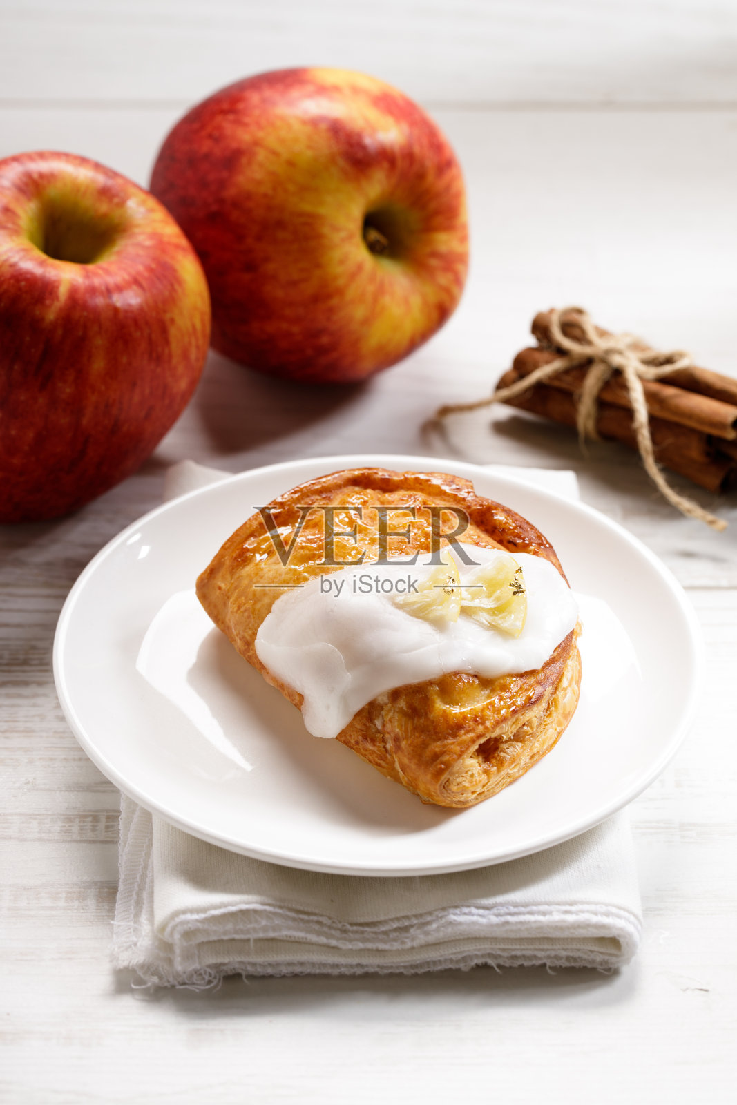 一块肉桂苹果派在一个白色的盘子上，以新鲜的苹果为背景，秋天的食物概念照片摄影图片
