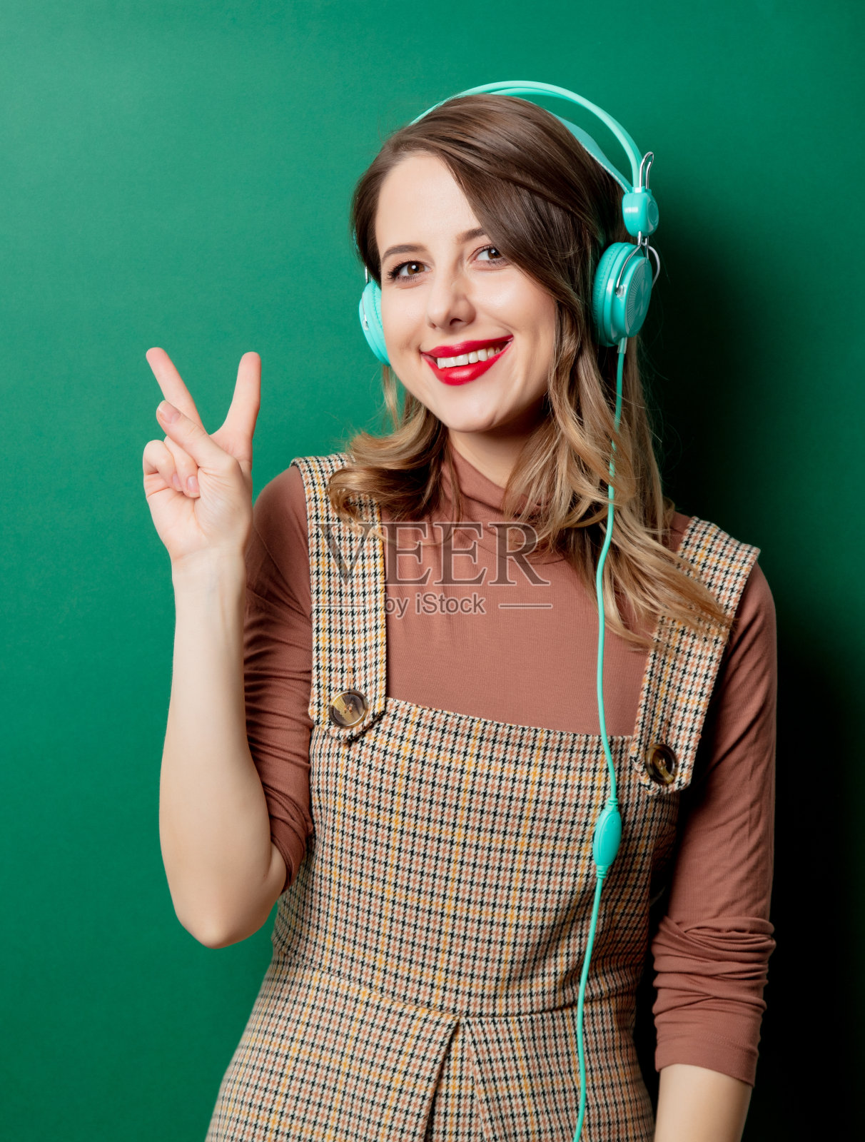 穿着复古服装，戴着耳机，背景是绿色的女人照片摄影图片