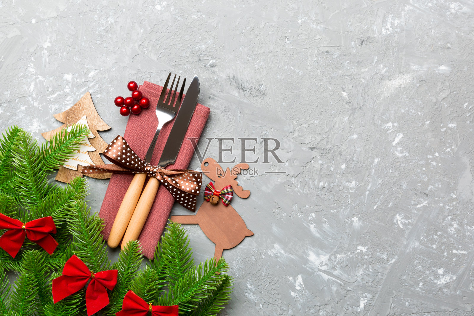 水泥背景上的假日物体俯视图。餐巾上用缎带绑起来的餐具。圣诞装饰和驯鹿的拷贝空间。年夜饭概念照片摄影图片