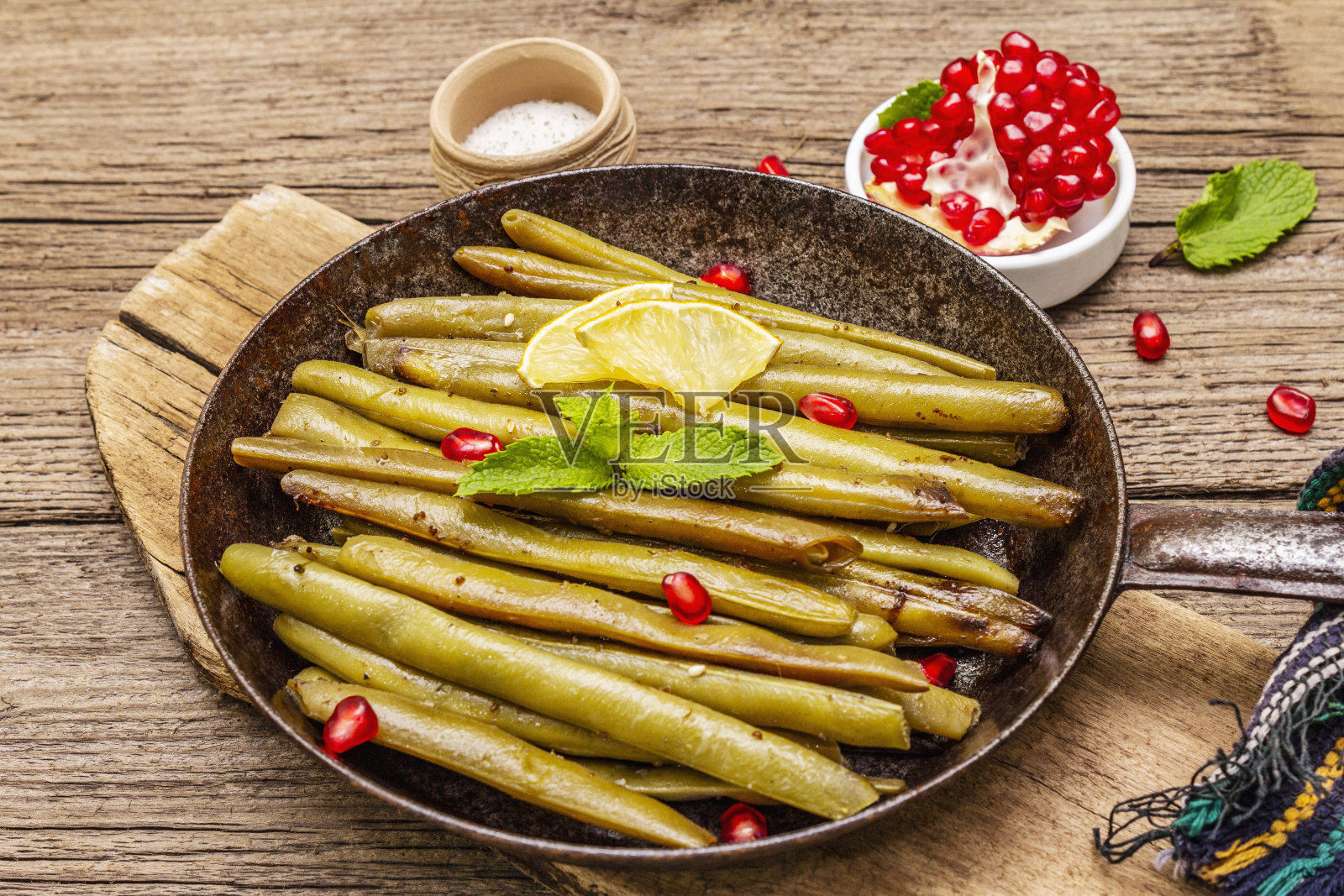 青豆与芝麻、薄荷、柠檬一起在平底锅中烘烤。健康的纯素(素食)食品概念。旧木板背景照片摄影图片