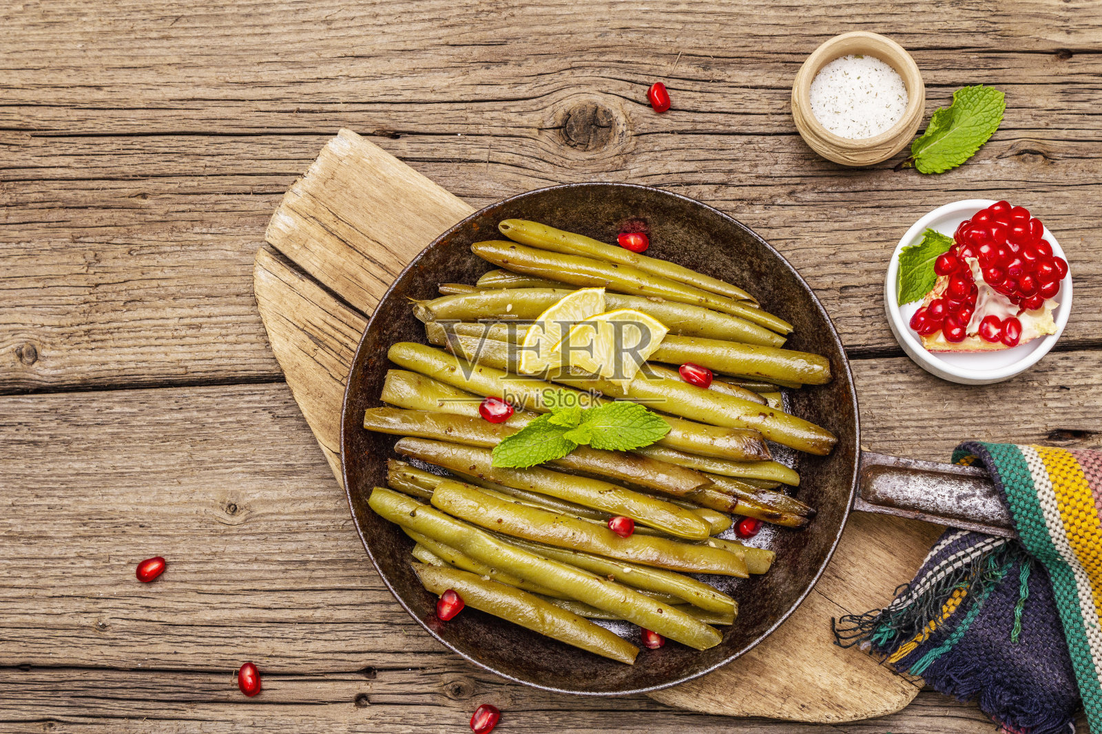 青豆与芝麻、薄荷、柠檬一起在平底锅中烘烤。健康的纯素(素食)食品概念。旧木板背景照片摄影图片