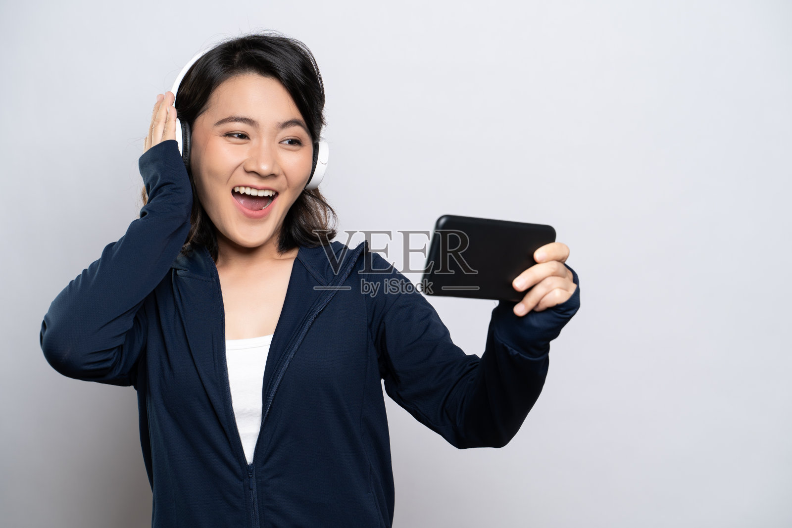 一个健康妇女的肖像使用智能手机玩游戏孤立的白色背景照片摄影图片