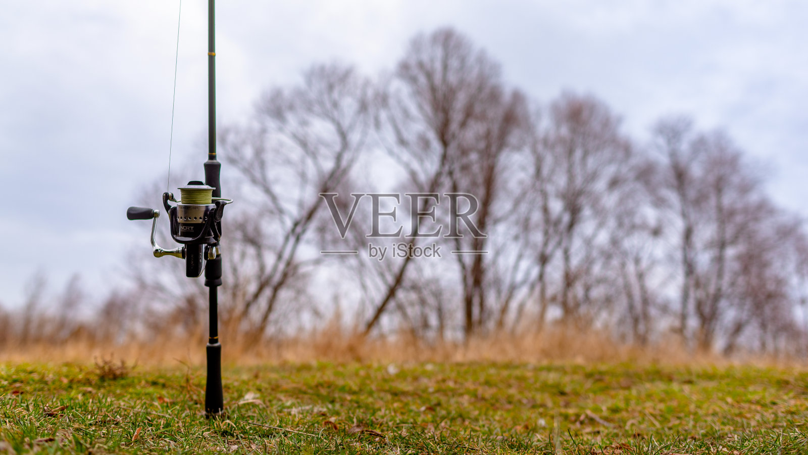 钓竿纺纱机的背景是秋天的田野和树木。照片摄影图片