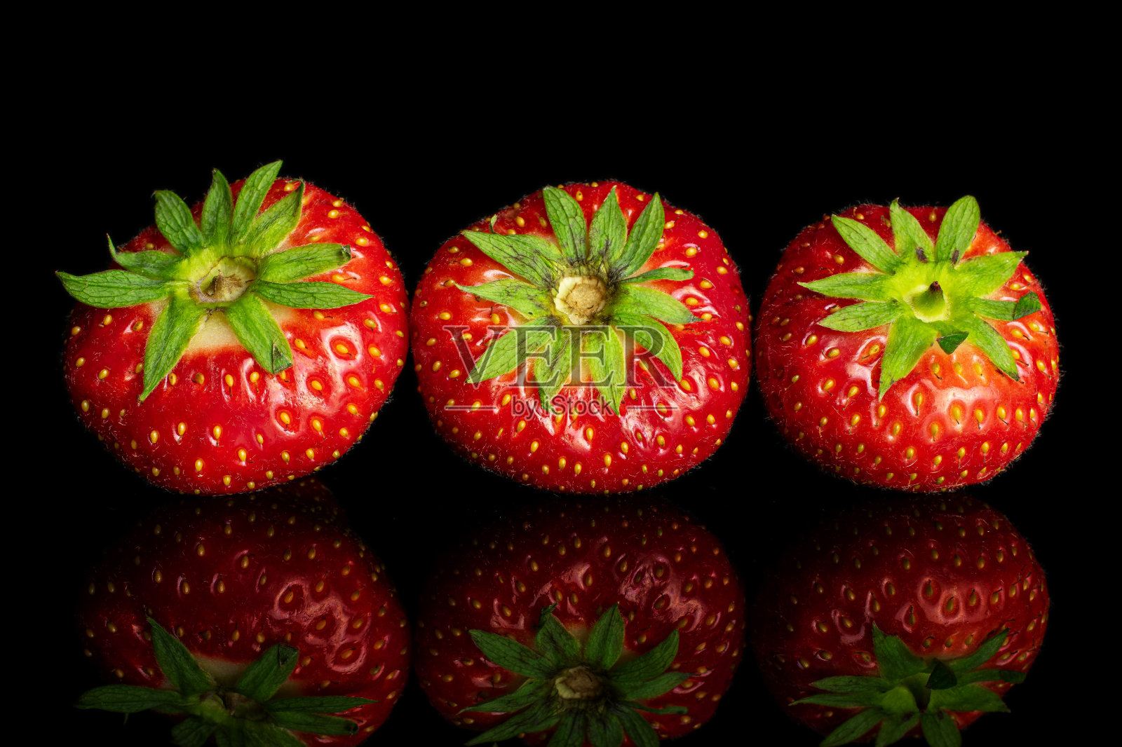 新鲜的红草莓孤立在黑色玻璃上照片摄影图片