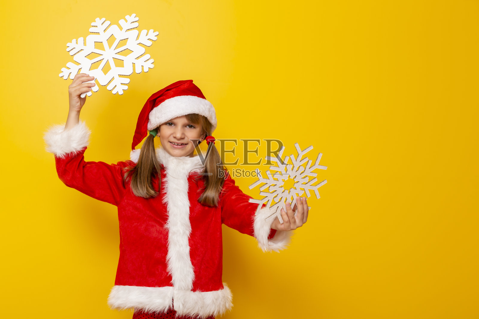 穿着圣诞老人服装的孩子拿着硬纸板雪花照片摄影图片