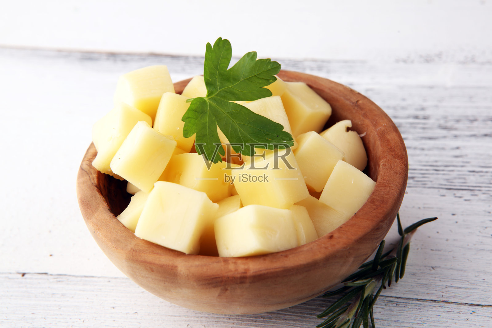 木碗里的芝士丁和欧芹。桌上的奶酪块照片摄影图片