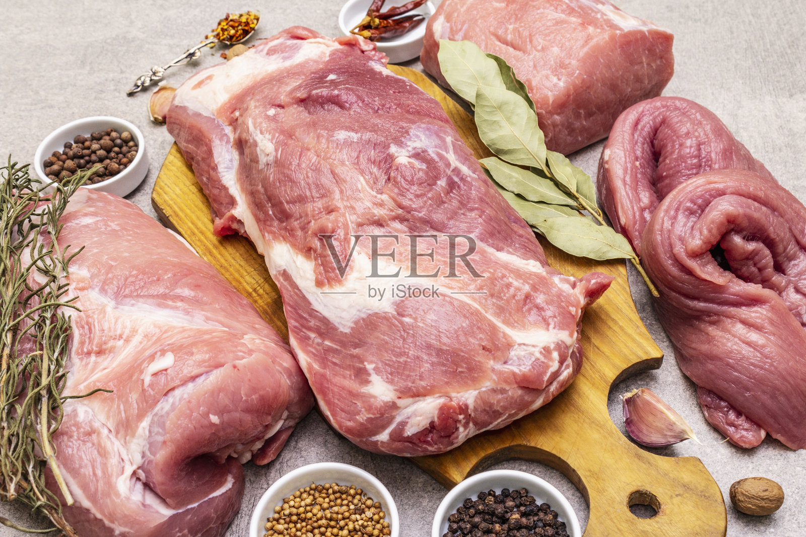 各种各样的新鲜猪肉。生肉加香料。里脊，肩胛骨，颈部，后腿牛排。石混凝土背景照片摄影图片