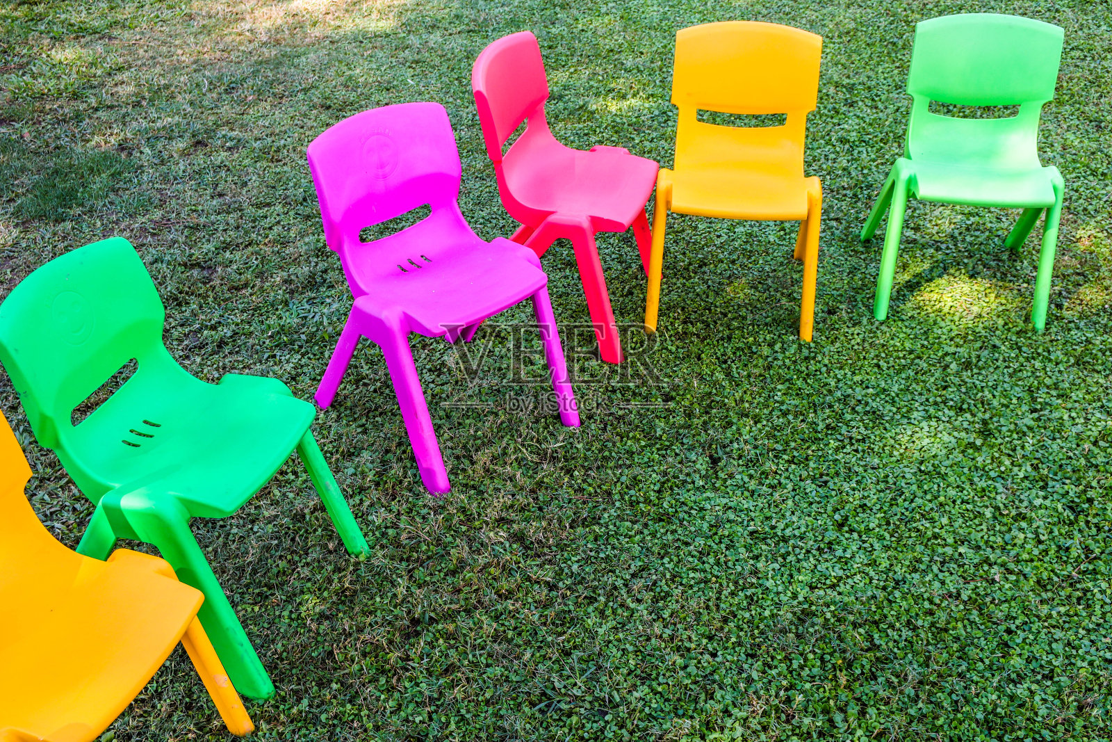 在绿色背景上，一排椅子排成半圆形。为孩子们的聚会做准备。照片摄影图片