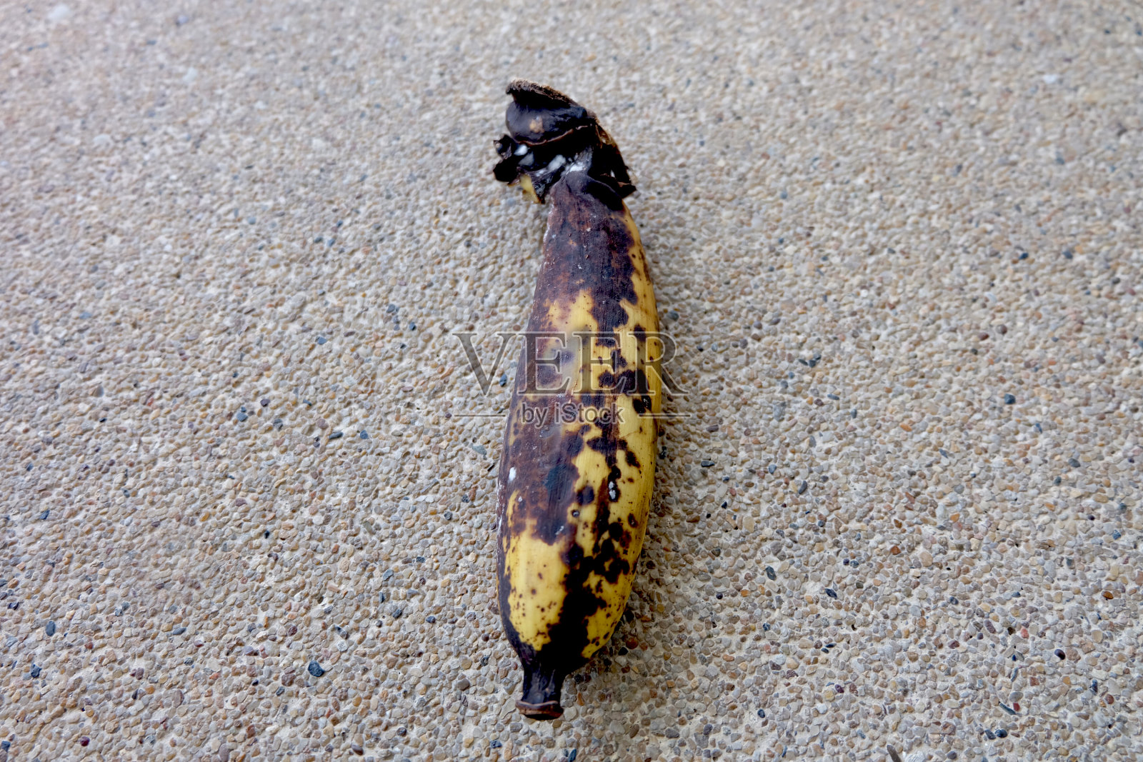 腐烂的香蕉-在人行道的背景或纹理上成熟过度的老香蕉。不健康的水果概念。照片摄影图片