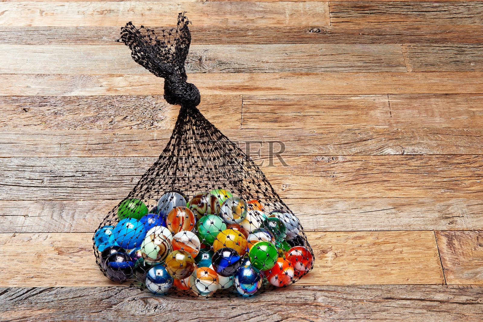 木桌上放着一袋彩色弹珠照片摄影图片