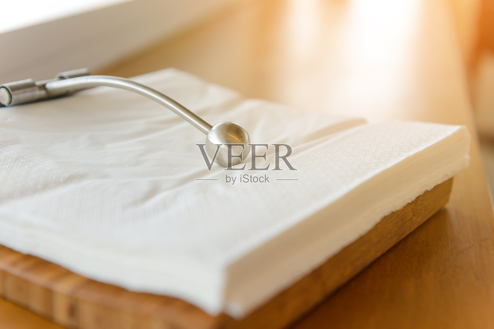 金属镇纸在白色方形餐巾纸上。现代纸巾架照片摄影图片