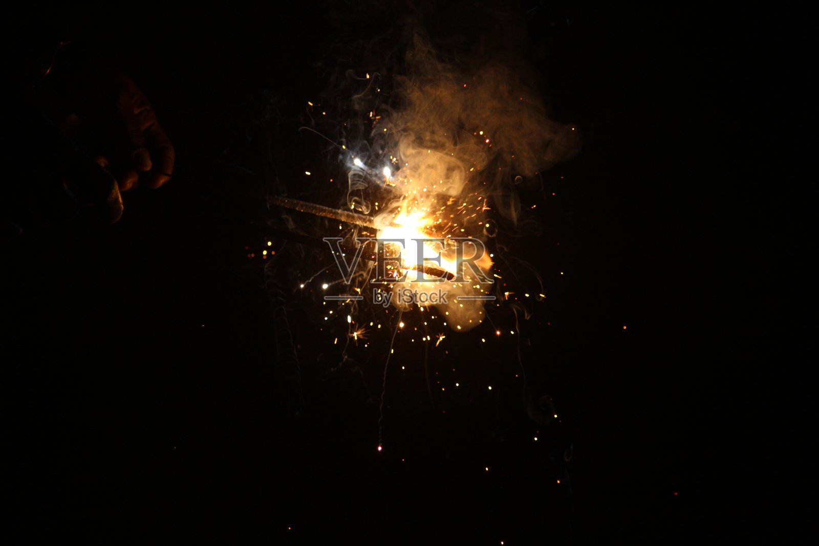 在黑暗的背景下，在一些白色的烟雾中，手持烟花的人在deepvalali / dewali庆祝活动上闪闪发光照片摄影图片