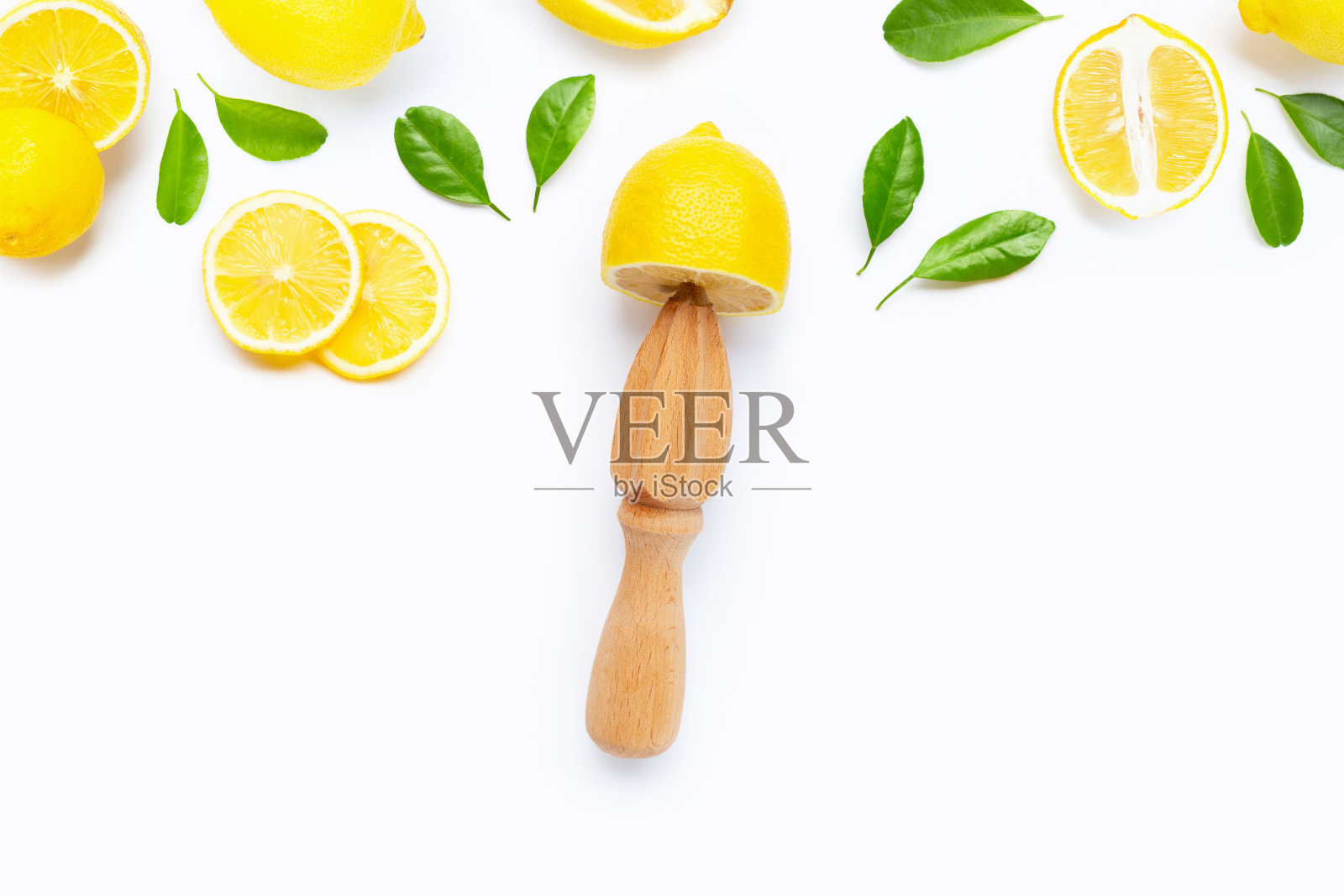 新鲜的柠檬和树叶与木制榨汁机在白色的背景。照片摄影图片