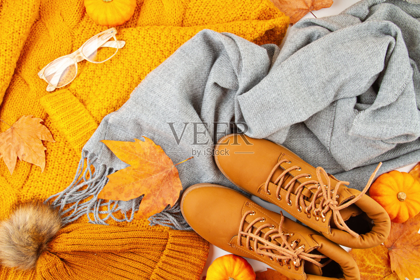 平铺秋天的构图与秋天的叶子，南瓜，靴子和温暖的羊毛围巾和毛衣照片摄影图片