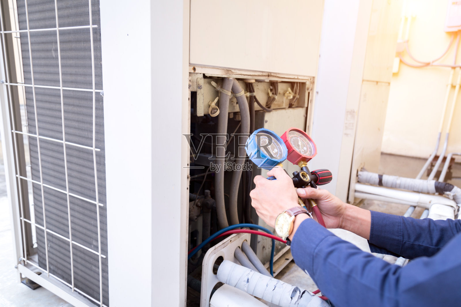 技术人员正在检查空调，测量设备是否充空调。照片摄影图片