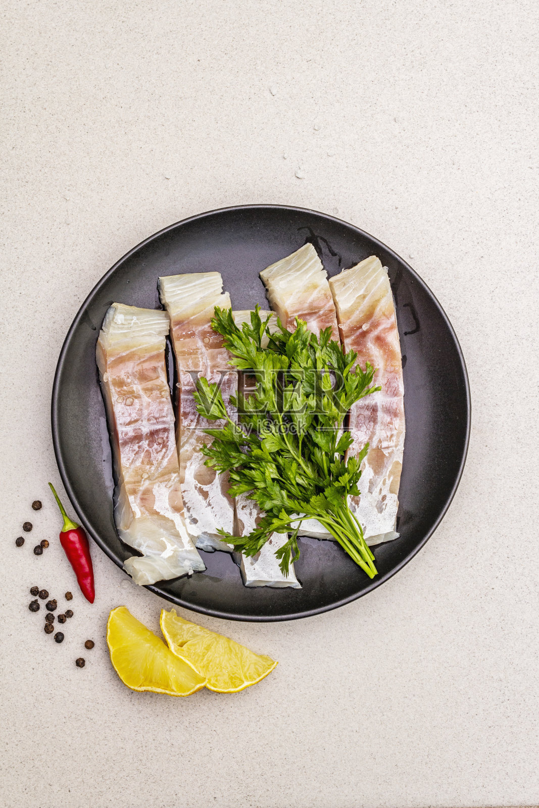 生鳕鱼片。新鲜的鱼是健康的饮食方式。柠檬，欧芹，海盐，辣椒，黑胡椒。石混凝土背景照片摄影图片