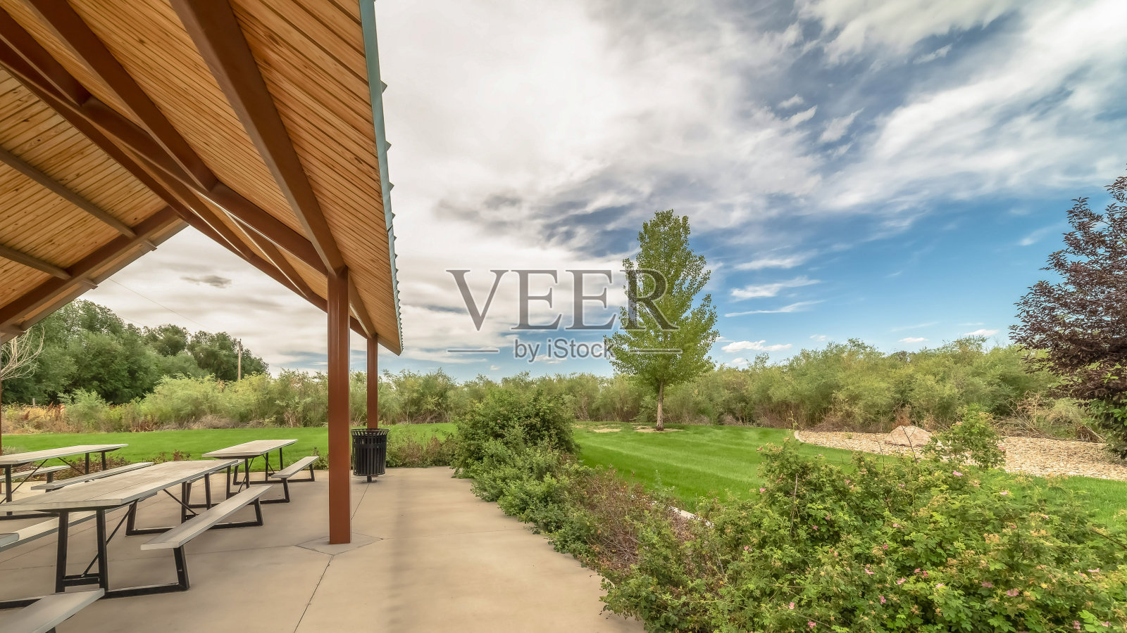 全景框架亭和用餐区在一个公园，云彩填充天空的背景照片摄影图片