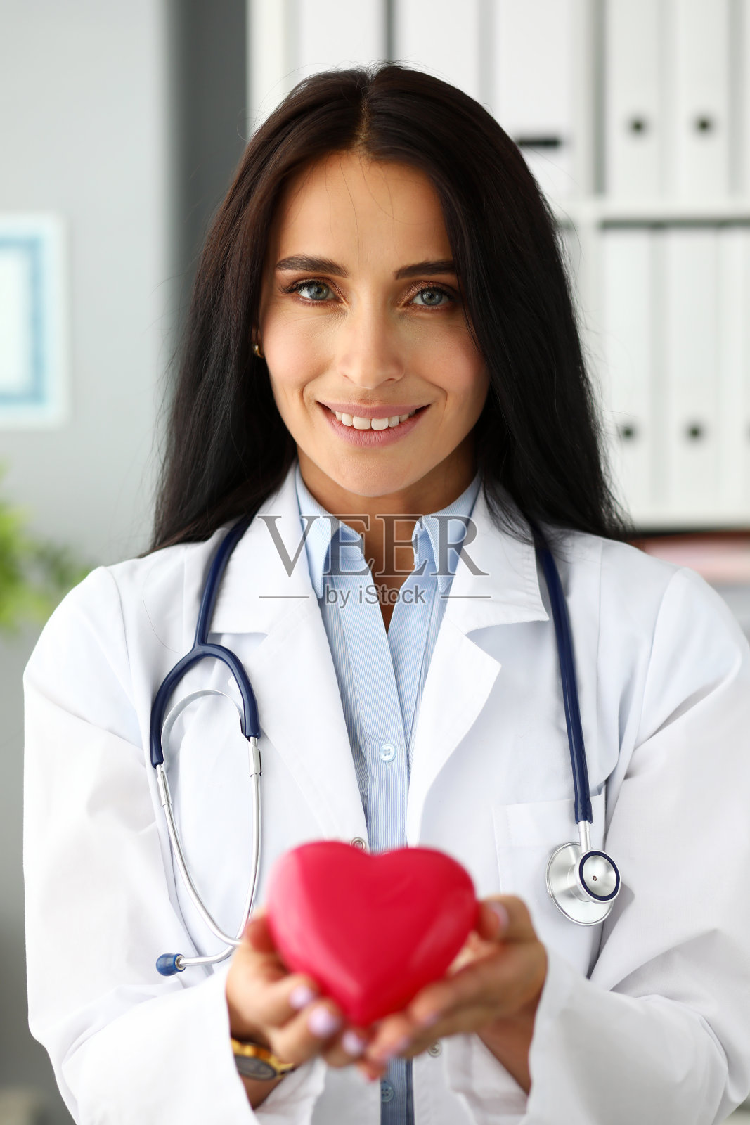 美丽微笑的GP手里拿着红色的玩具心照片摄影图片