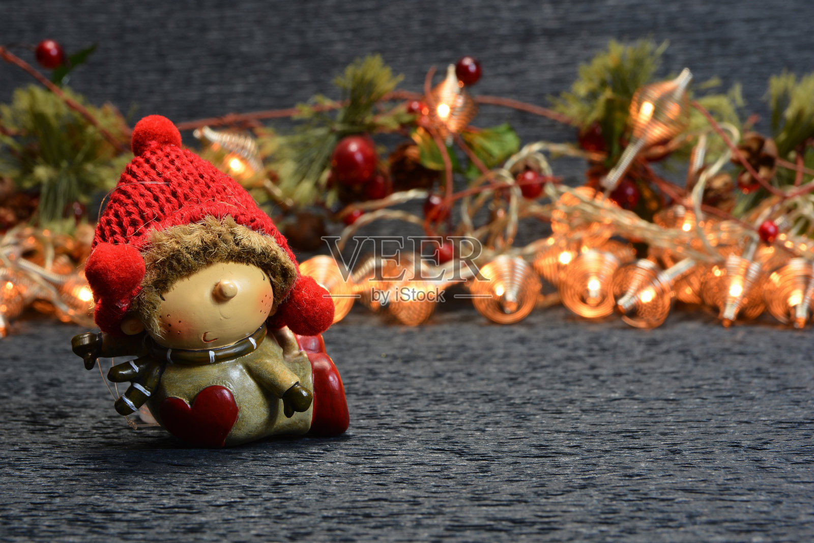 圣诞玩具在红帽子的背景上发光的花环和冷杉树枝与红色的浆果在黑暗的背景照片摄影图片