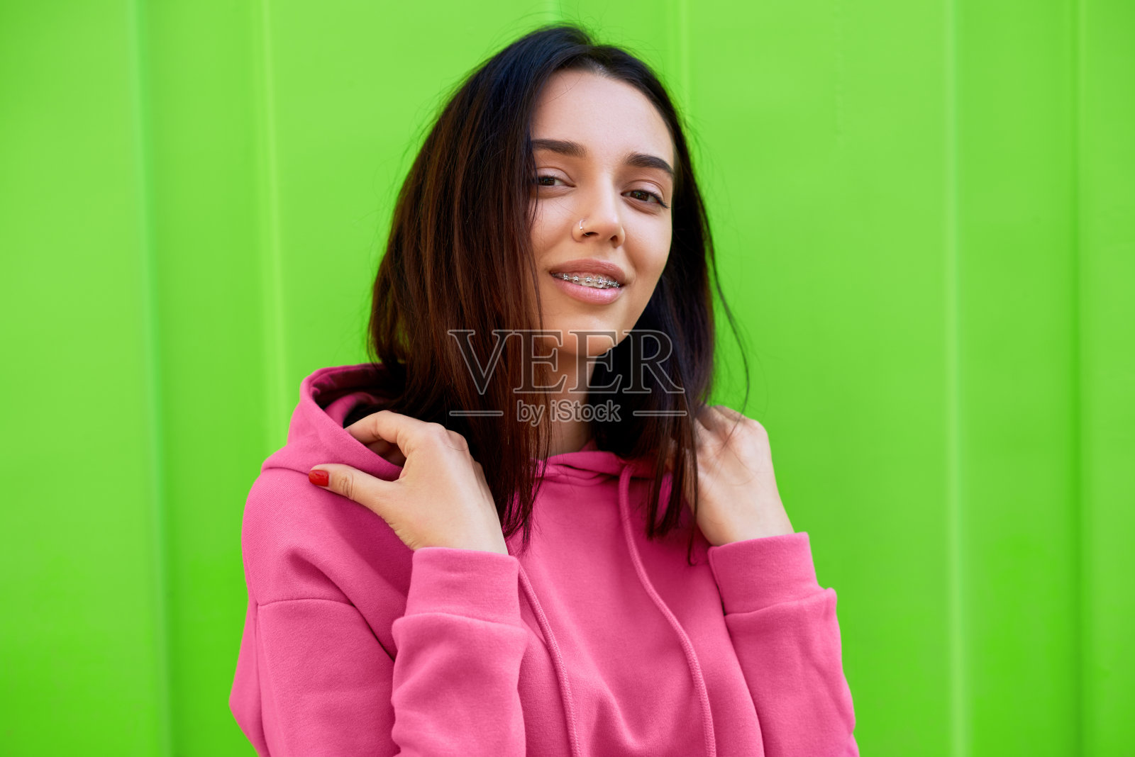 年轻女孩在外面散步时看着镜头微笑的肖像。户外肖像美丽的女性有快乐的表情摆在绿色的背景。照片摄影图片