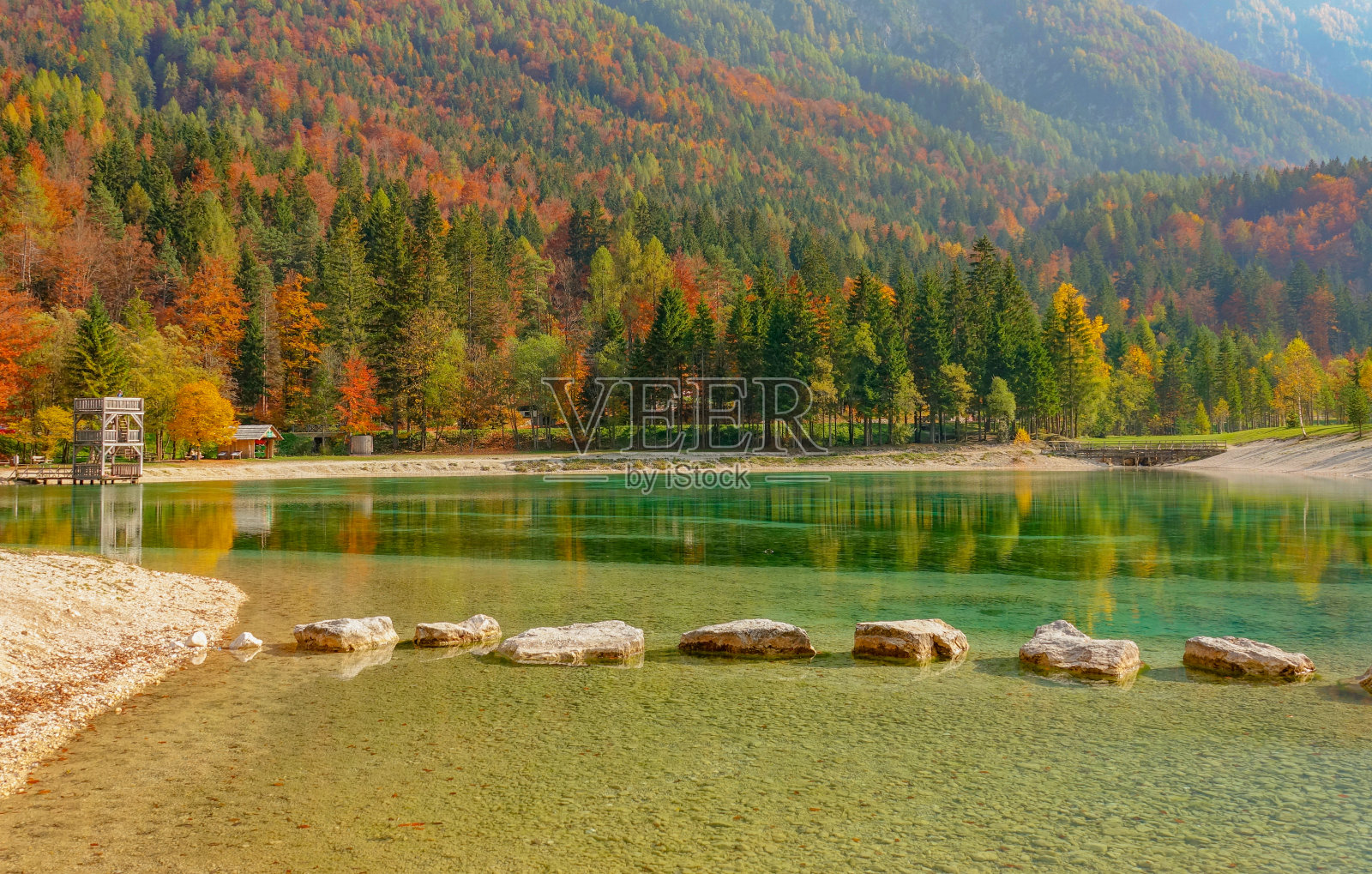 巨大的石头在色彩斑斓的森林中形成了一条穿越美丽湖泊的小路。照片摄影图片