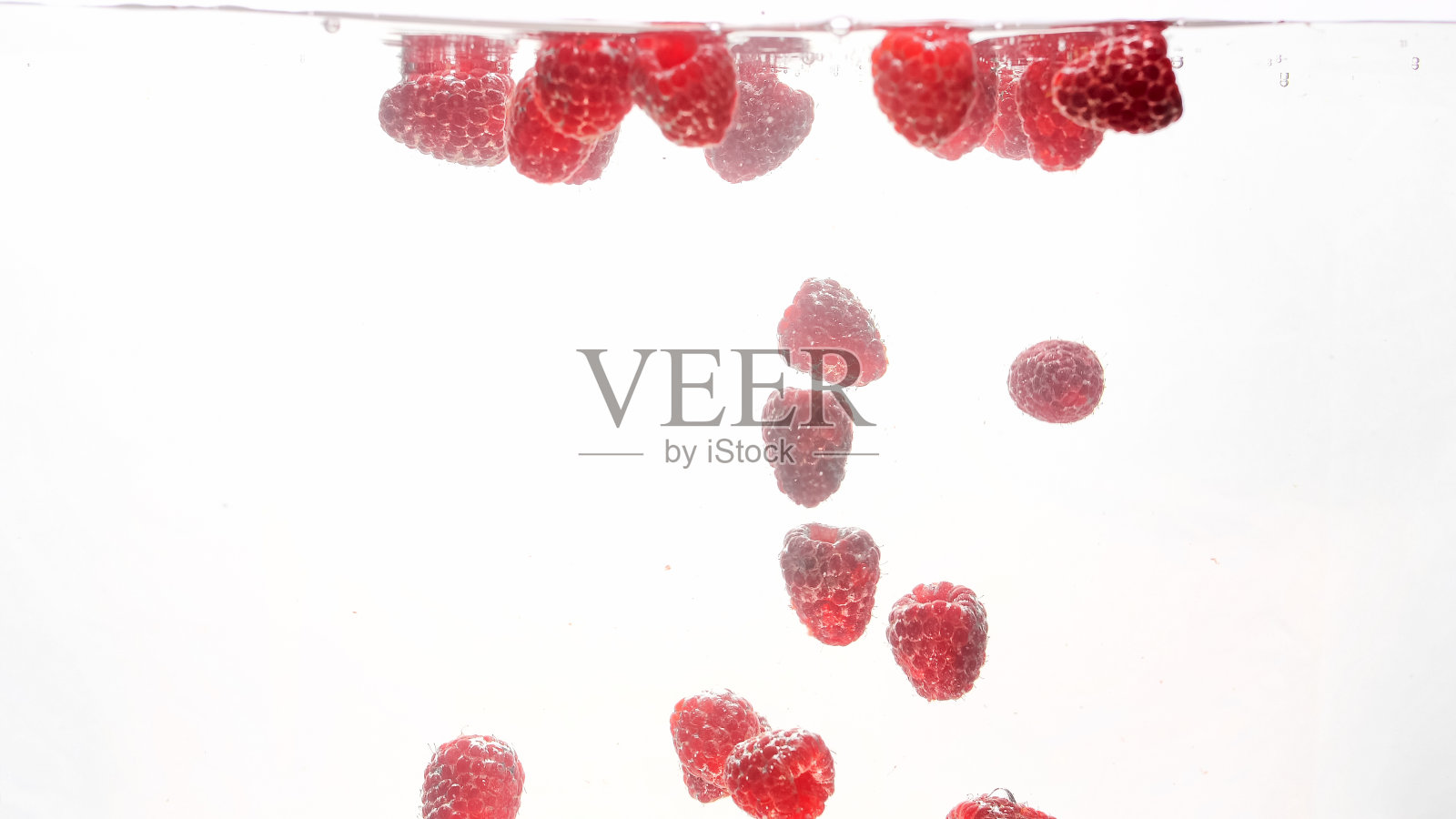 特写图像的许多新鲜成熟的树莓下落和溅水在白色的背景照片摄影图片